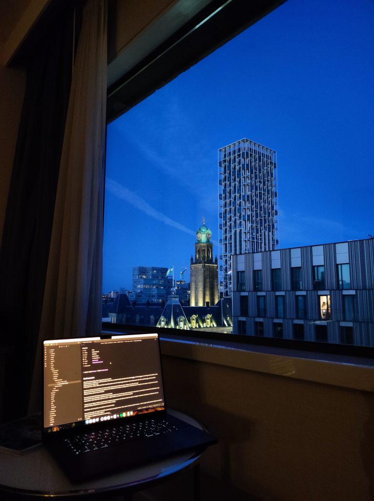 Un computer aperto davanti alla finestra, con le luci di Rotterdam al calare della sera.